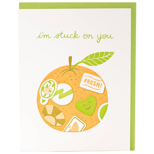 Greeting card with white background and image of an orange with stickers on it with green text says, "I'm stuck on you". Green envelope included. 