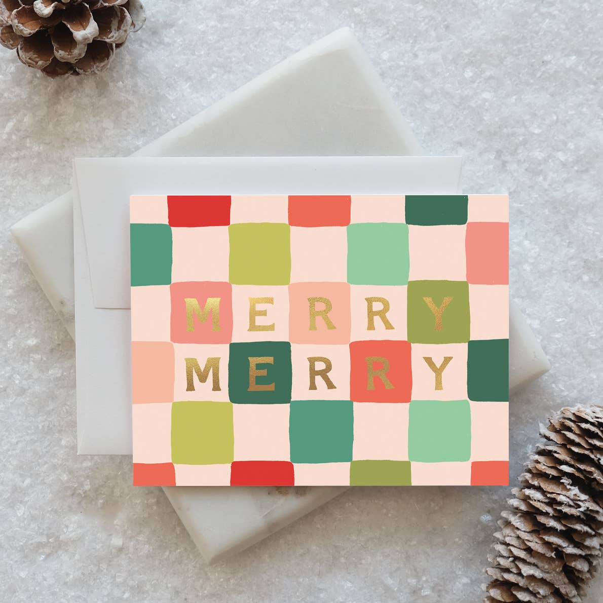 Greeting card with checkerboard background in pink, green, peach and red with gold foil text says, "Merry Merry". Envelopes included. 