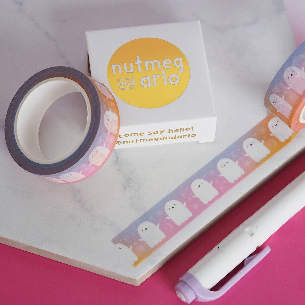 Image of roll of Washi tape with lilac and pink gradient background with images white ghosts with black outlined faces. 