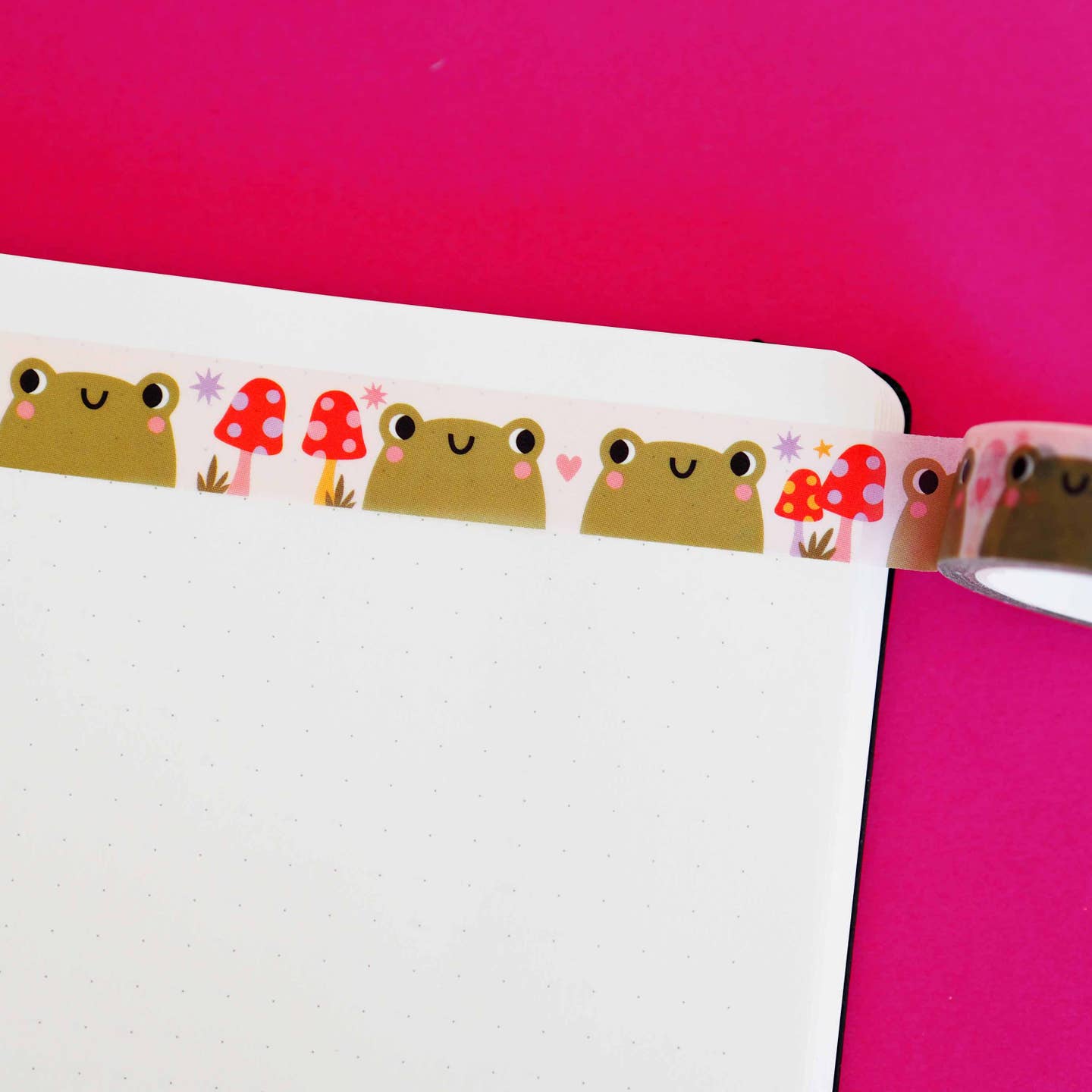 Washi tape with white background and images of olive green frogs and red polka dot toadstools.