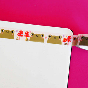 Washi tape with white background and images of olive green frogs and red polka dot toadstools.