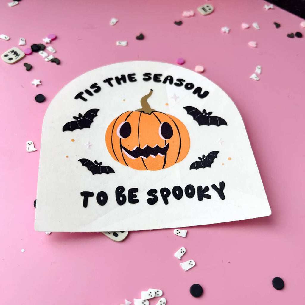 White background with orange jack o'lantern and black bats with black text says, "Tis the season to be spooky". 