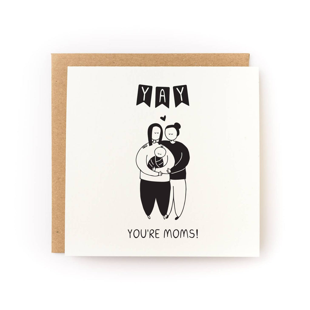 Greeting card with cream background with image of two women holding a baby. Black text says, "Yay You're Moms!". Kraft envelope is included. 