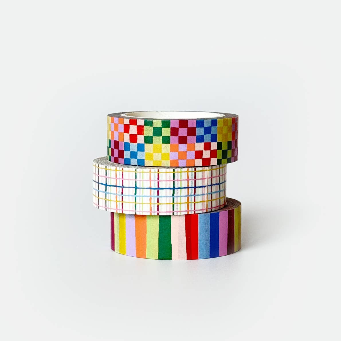Stack of three washi tapes, rainbow colors in checkerboard, plaid and striped. 