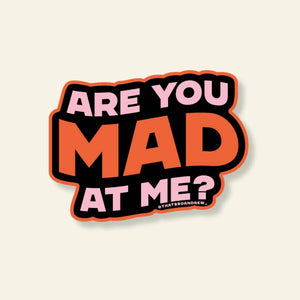 Decorative sticker with black background and orange border with pink text says, "Are you ...at me?" Orange text says, "Mad". 