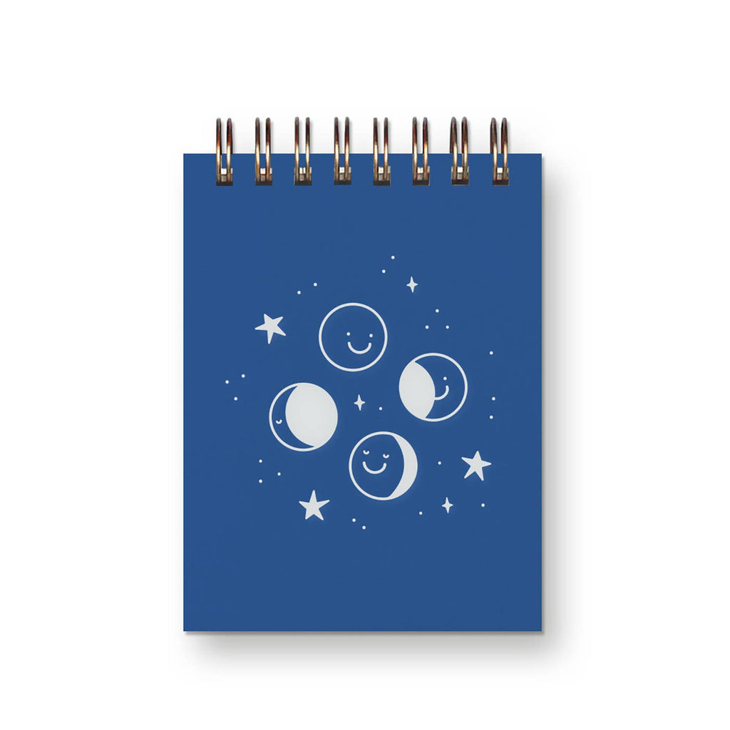 Pocket notebook with blue cover and white images of phases of moon with coiled binding at top.
