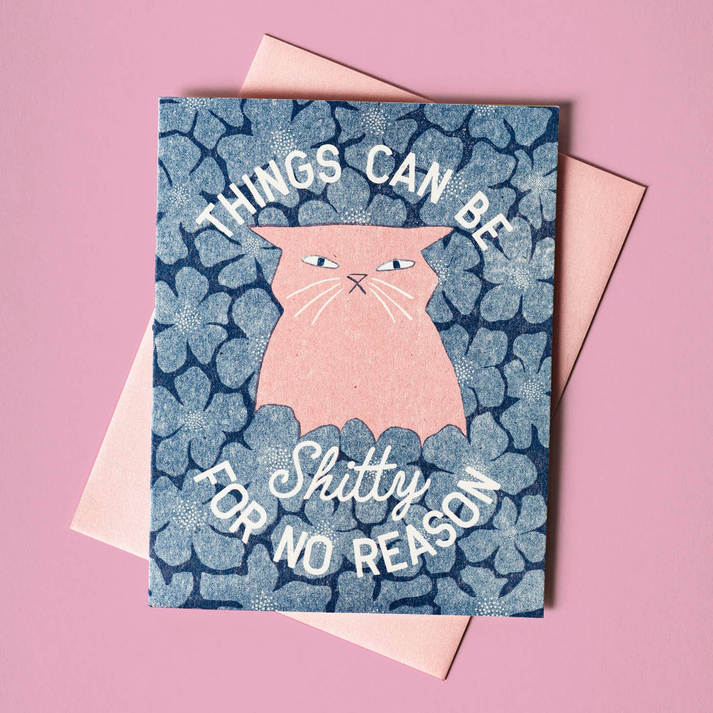 Blue background with image of pink cat with white text says, "Things can be shitty for no reason". Pink envelope is included,. 