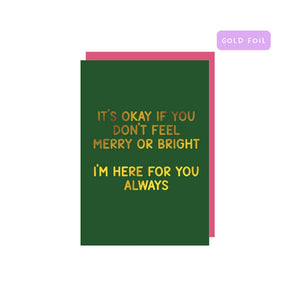 Greeting card with green background and gold foil text says, "It's okay if you don't feel merry or bright, I'm here for you always". Pink envelope included. 