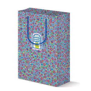 Gift bag with flowered background in blue, red, pink with image of an open window with a green frog sitting in it. Blue handles. 