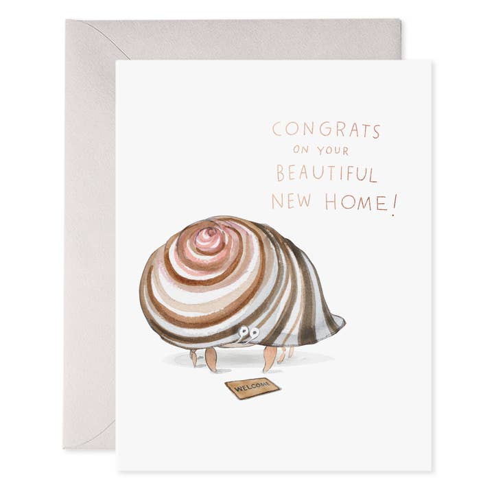 Greeting card with white background and image of a hermit crab  and a welcome mat with gold foil text says, "Congrats on your beautiful new home!".  Grey envelope included. 