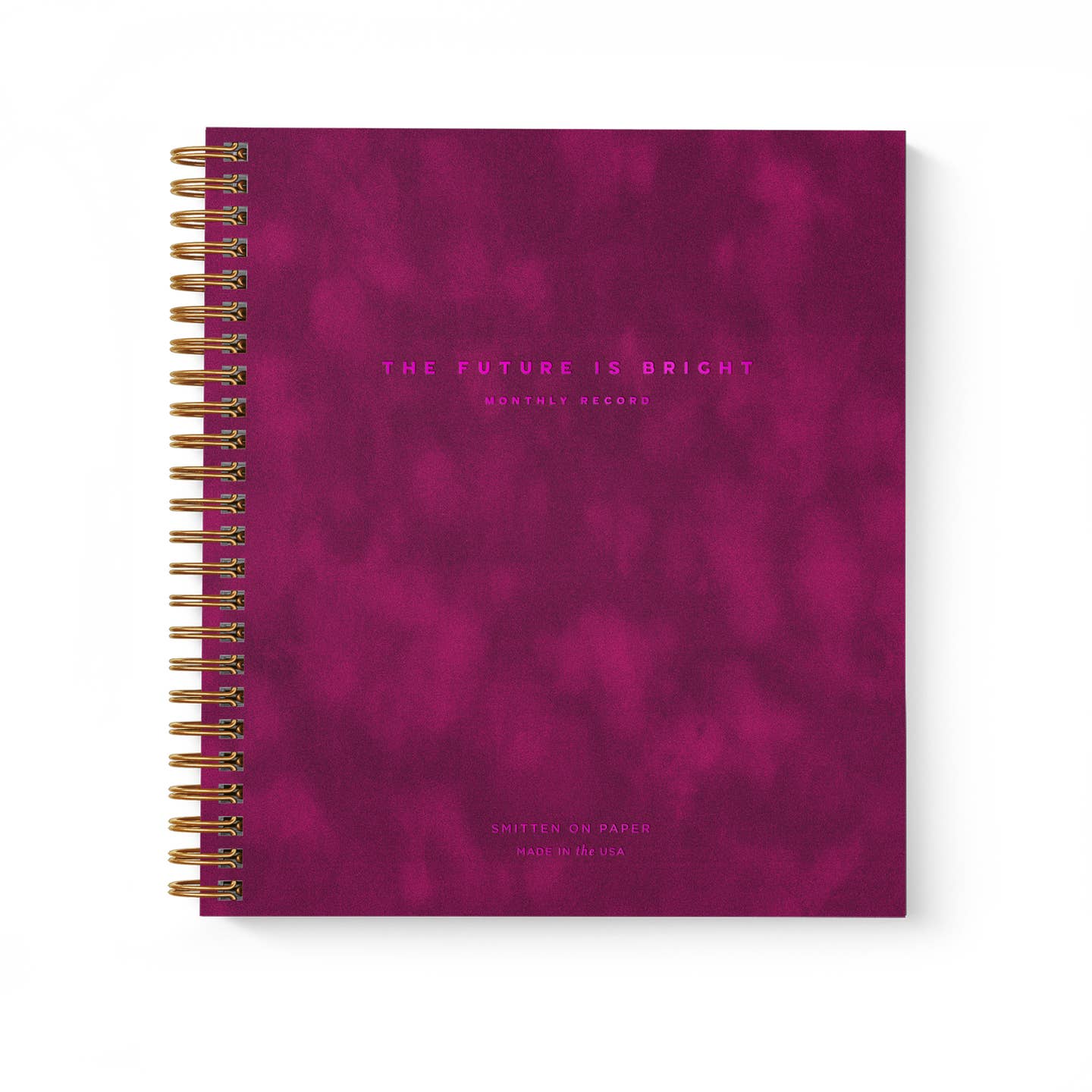 Planner with burgundy cover and hot pink text says, "The Future is bright, monthly planner" with gold coil binding on side.