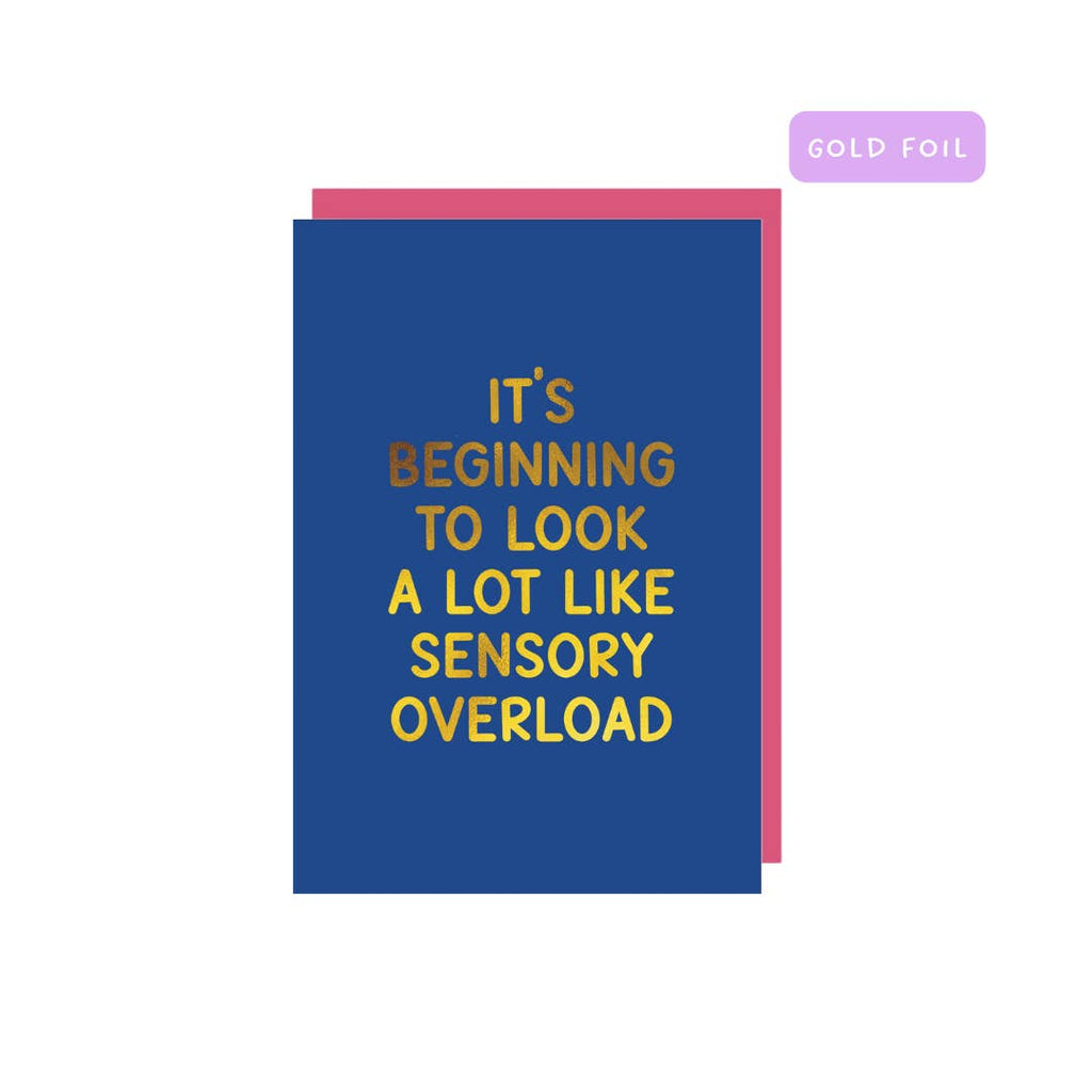 Greeting card with blue background and gold foil text says, "It's beginning to look a lot like sensory overload". Pink envelope included. 