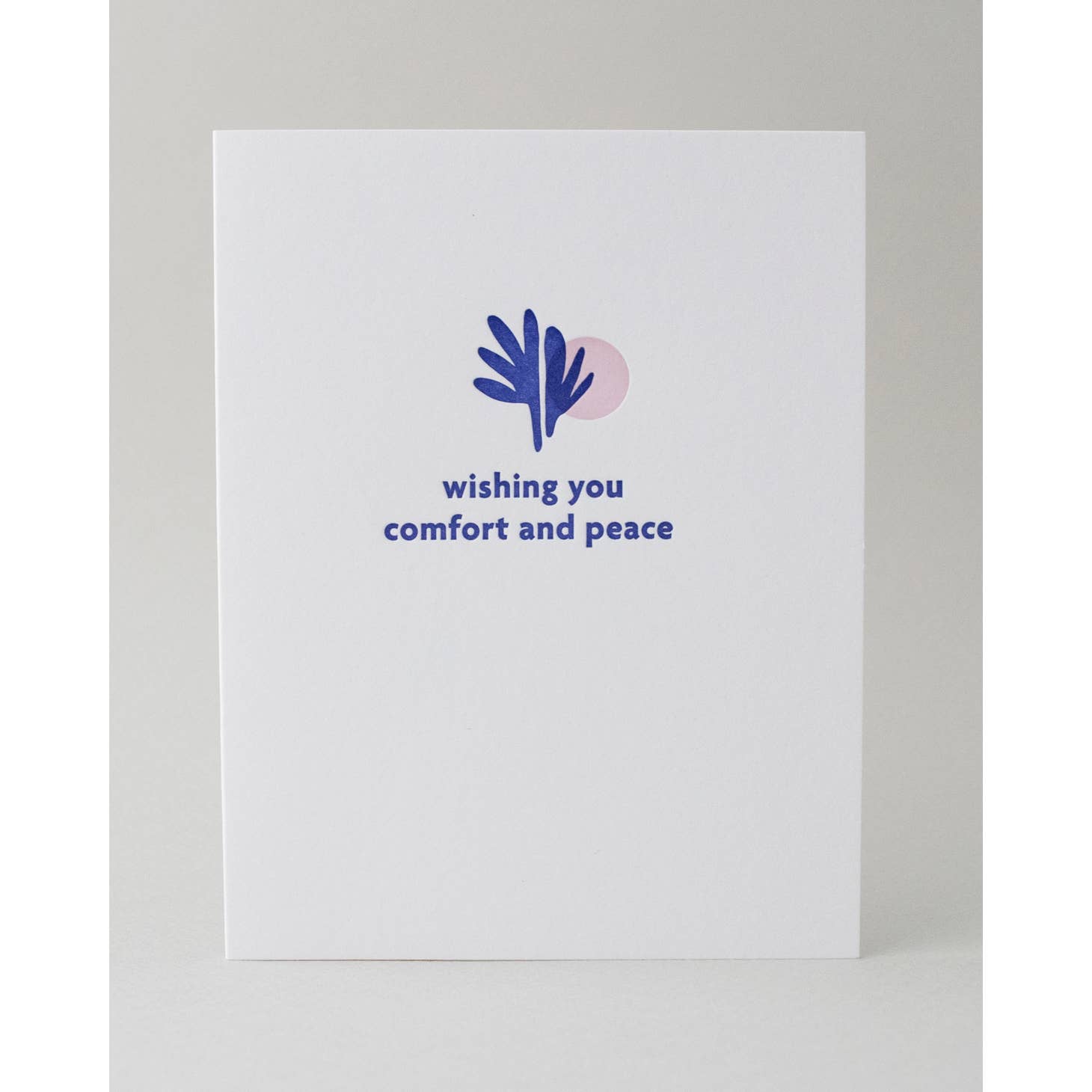 White background with image of blue leaves and pale pink circle with blue text says, "Wishing you comfort and peace". Envelope is included.
