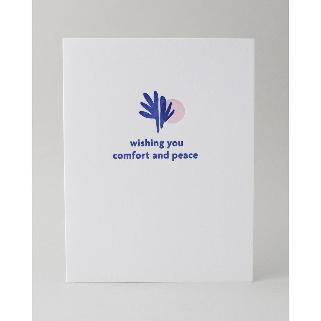 White background with image of blue leaves and pale pink circle with blue text says, "Wishing you comfort and peace". Envelope is included.