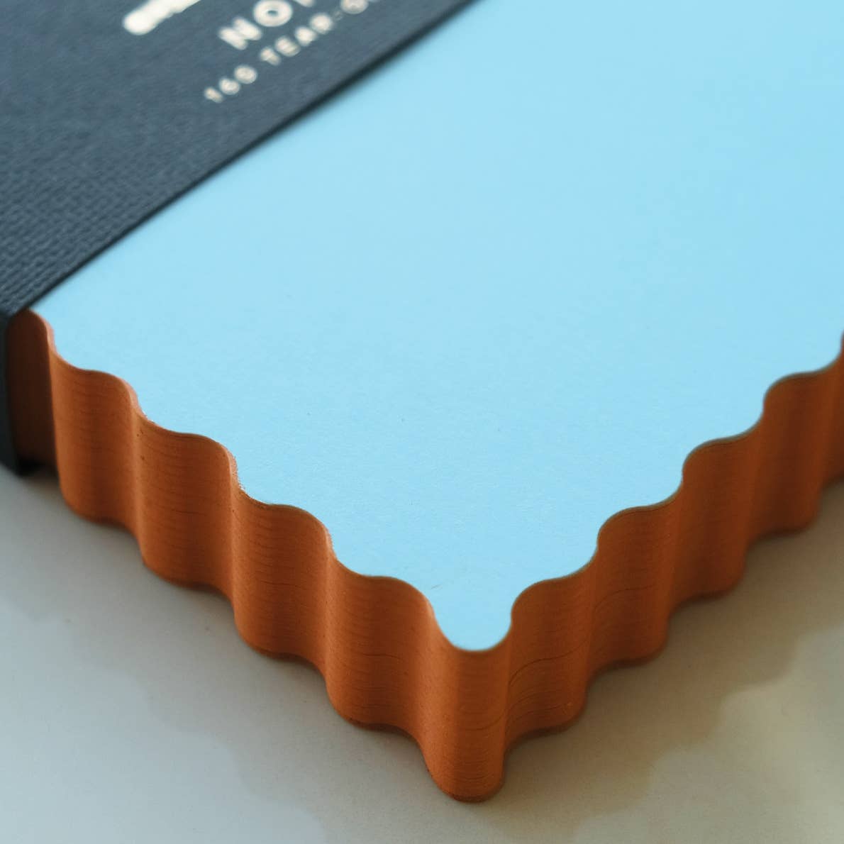 Notepad with blue background and orange wavy edging. 