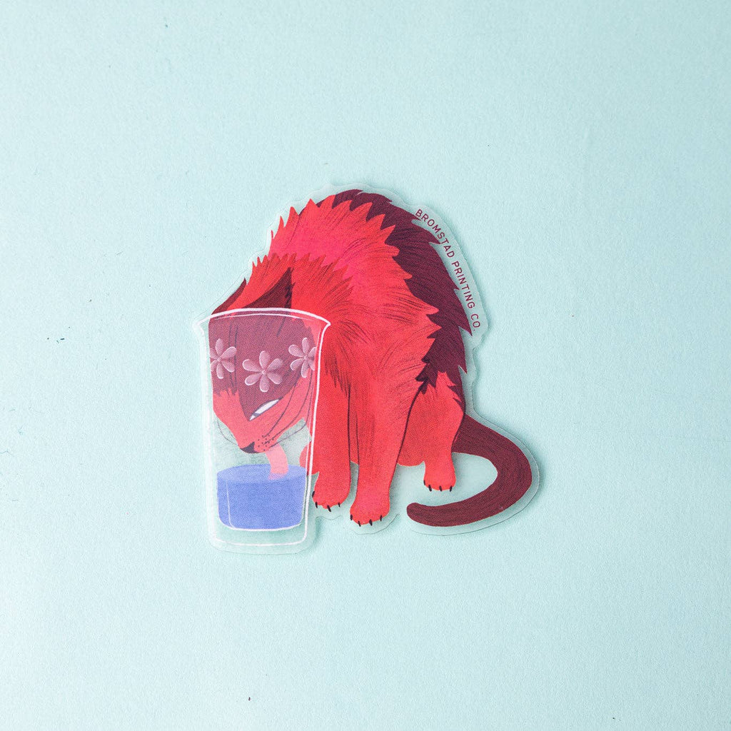 Decorative sticker with image of a red and burgundy cat with its head in a glass of water licking up the water. 