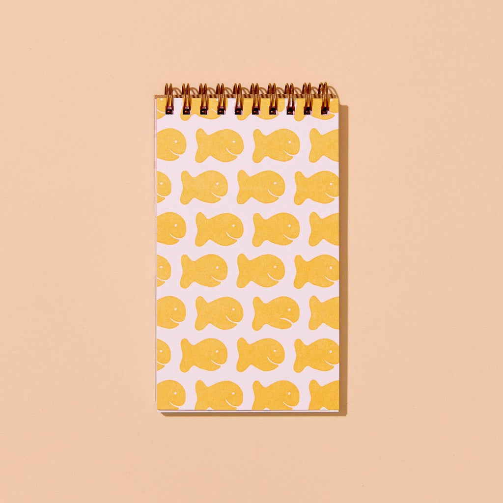 Notebook with images of orange goldfish crackers on white background with coiled binding at top. 