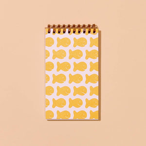 Notebook with images of orange goldfish crackers on white background with coiled binding at top. 