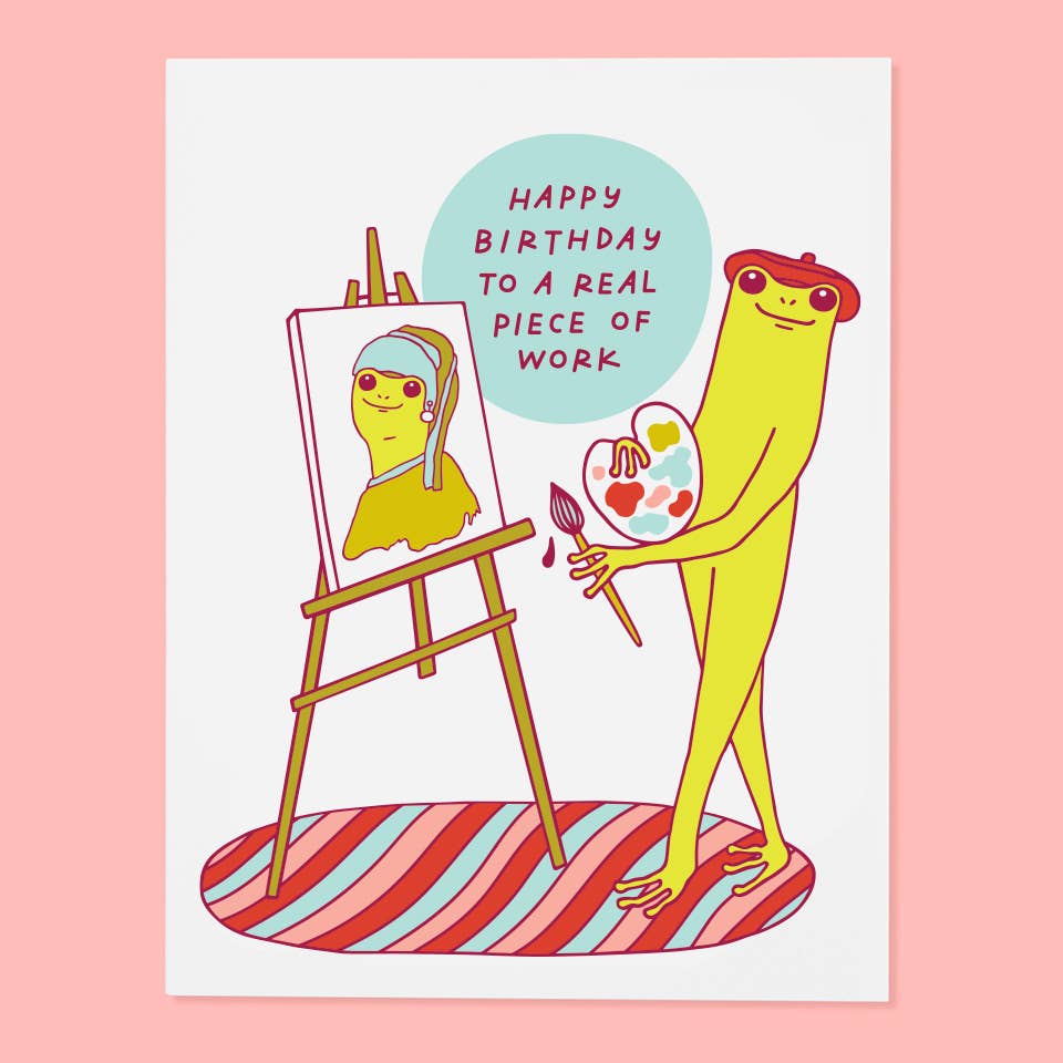 Greeting card with white background and iamge of a frog with a paint palette painting a picture on an easel with red text says, "Happy Birthday to a real piece of work". Envelope included.