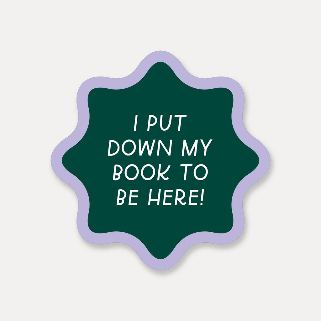 Decorative sticker with green background and lilac border with white text says, "I put down my book to be here!".