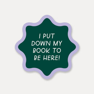 Decorative sticker with green background and lilac border with white text says, "I put down my book to be here!".