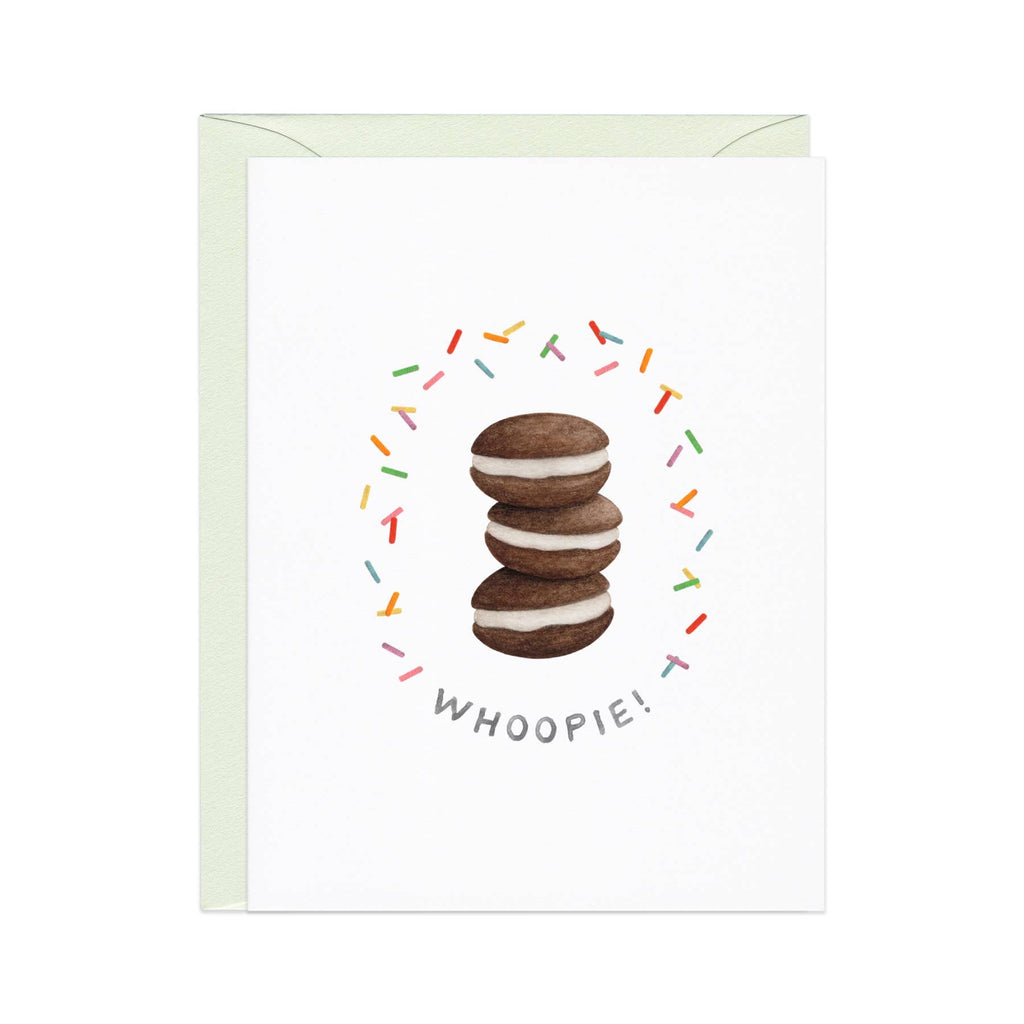 Greeting card with white background and image of three whoopee pies with sprinkles around them and grey text says, "Whoopie!". White envelope included.