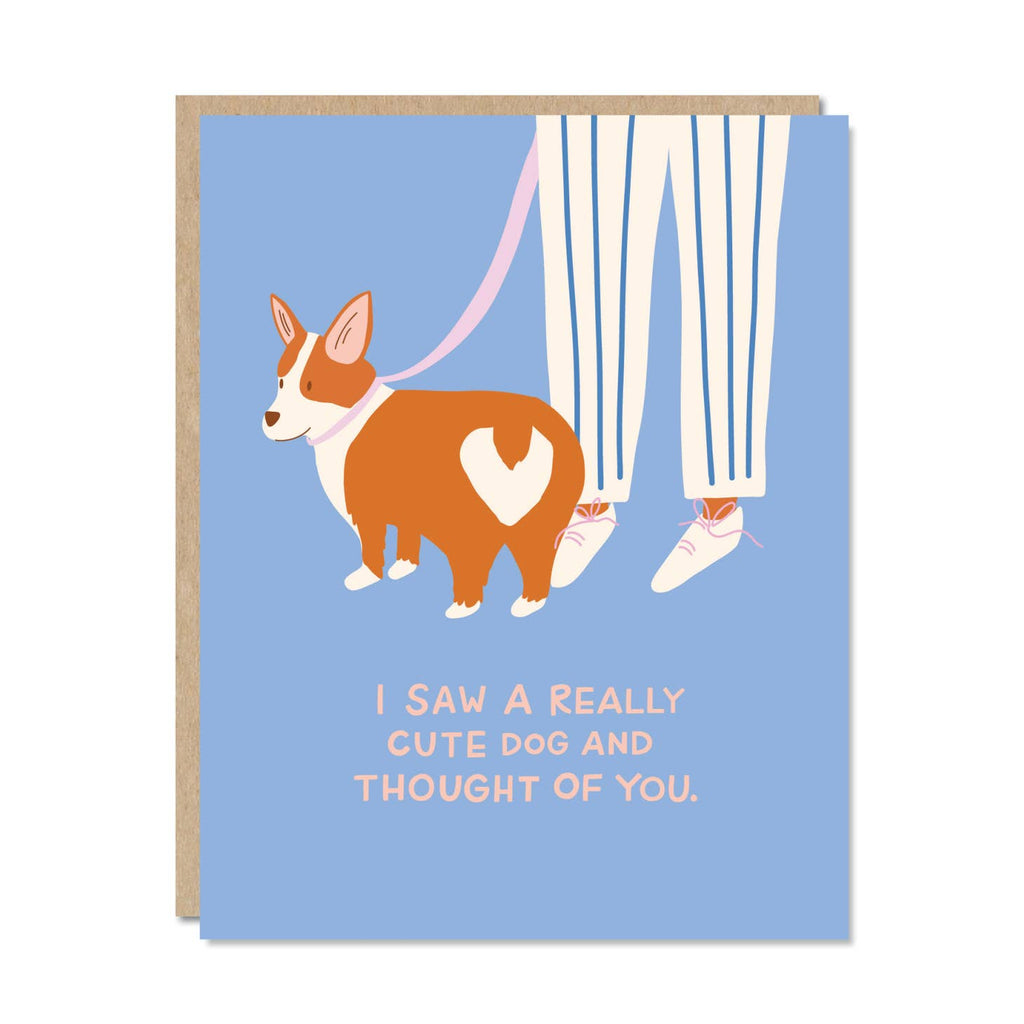 Greeting card with light blue background and image of brown and white dog on a leash with a pair of legs and pink text says, "I saw a really cute dog and thought of you.". Kraft envelope included. 
