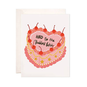 White background with image of a pink and red heart shaped birthday cake decorated with cherries and stars with black text says, “HBD to the baddest bitch”. White envelope included. 