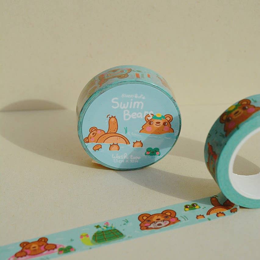 Image of roll of washi tape with blue background and images of brown bears swimming with a float and a green turtle. 