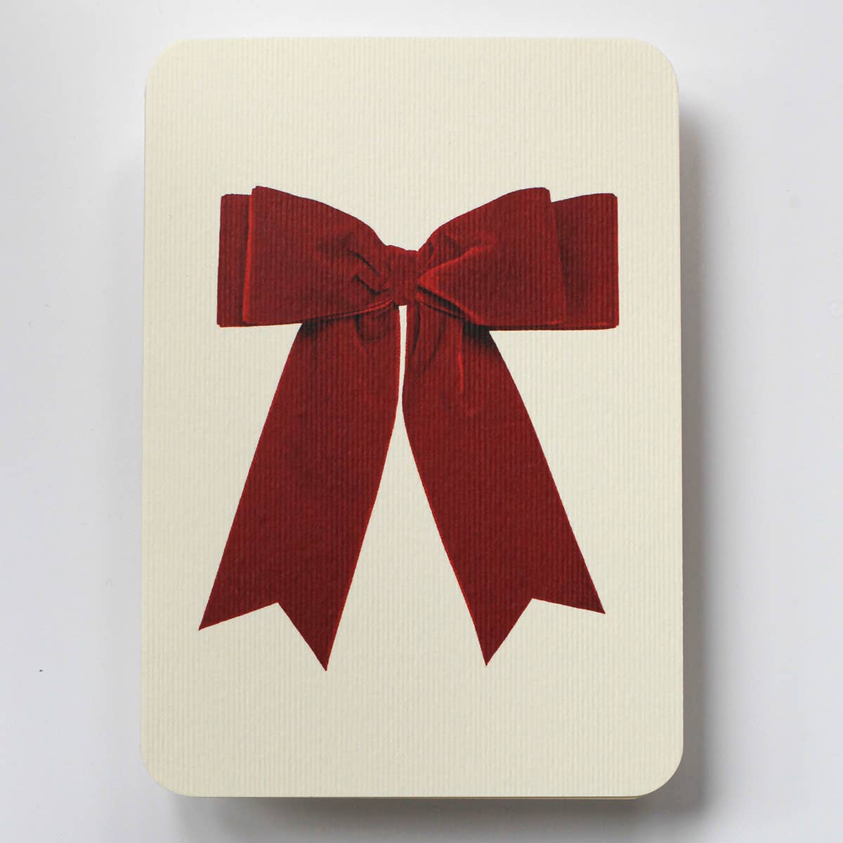 Greeting card with cream background and image of red velvet bow in center. Envelope included.