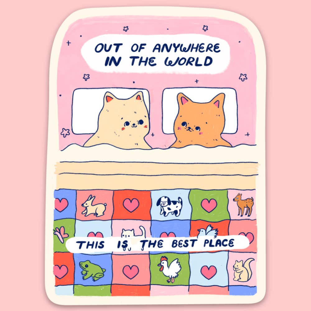Sticker with pink background and cream border with image of two cats in bed with a quilt with squares including animal images and black text says, "Out of anywhere in the world, this is the best place". 