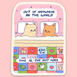 Sticker with pink background and cream border with image of two cats in bed with a quilt with squares including animal images and black text says, "Out of anywhere in the world, this is the best place". 