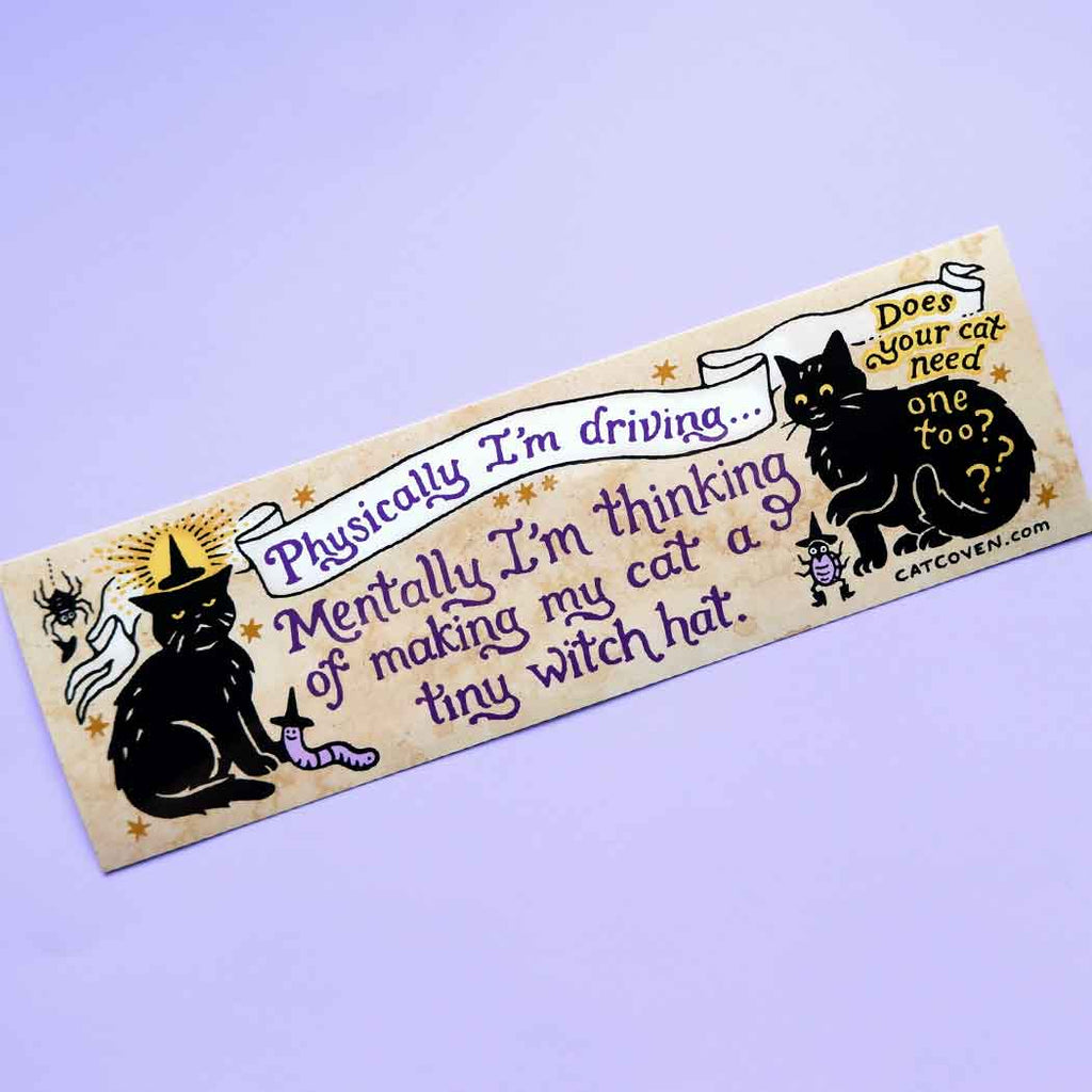 Decorative sticker with tan background and images of black cats and purple text says, "Physically I'm driving... mentally I'm thinking of making my car a tiny witch hat." and black text says, "Does your cat need one too?". 