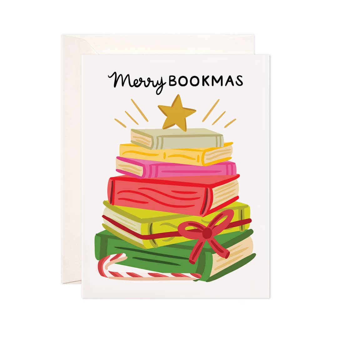 White background with image of stack of books in various colors to look like a tree with a gold star on top with black text says, “Merry Bookmas”. White envelope is included.      