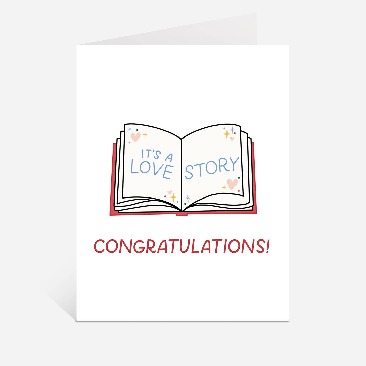 Greeting card with white background and image of an open book with blue text says, "It's a love story". Red text says, "Congratulations!". Envelope included.