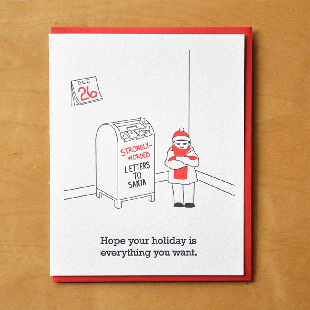 Greeting card with white background and image of a person with arms folded looked unhappy standing next to an overstuffed mailbox with red and black text says, "Strongly-worded letters to Santa" and a wall calendar with Dec 26 date. Black text says, "Hope your holiday is everything you want.". Envelope included. 