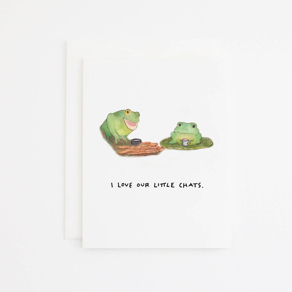 Greeting card with white background with images of two green frogs having a hot beverage and black text says, "I love our little chats." White envelope included. 