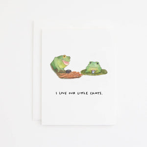Greeting card with white background with images of two green frogs having a hot beverage and black text says, "I love our little chats." White envelope included. 