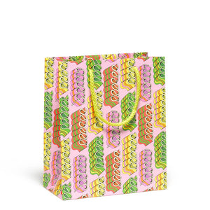 Gift bag with pink background and images of candy ribbons in green, yellow, orange and pink with yellow cord handle. 