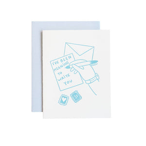 Greeting card with white background and blue image of a hand writing a note card with an envelope and blue text says, "I've been meaning to write to you". Blue envelope included.