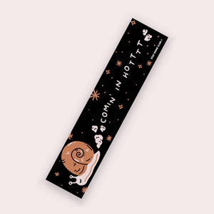 Decorative sticker with black background and image of a brown and tan snail. White text says, "Comin' in Hotttt".