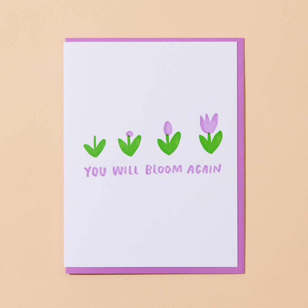 Greeting card with white background  and images of four flowers in stages of blooming with pink text says, "You will bloom again". Bright pink envelope included.