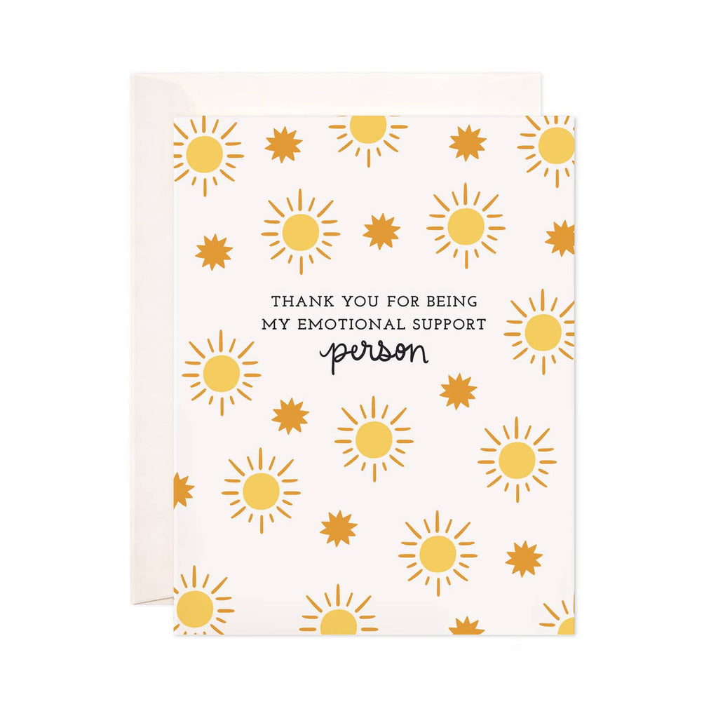 Greeting card with white background with images of yellow suns and orange bursts with black text says, "Thank you for being my emotional support person". White envelope included. 