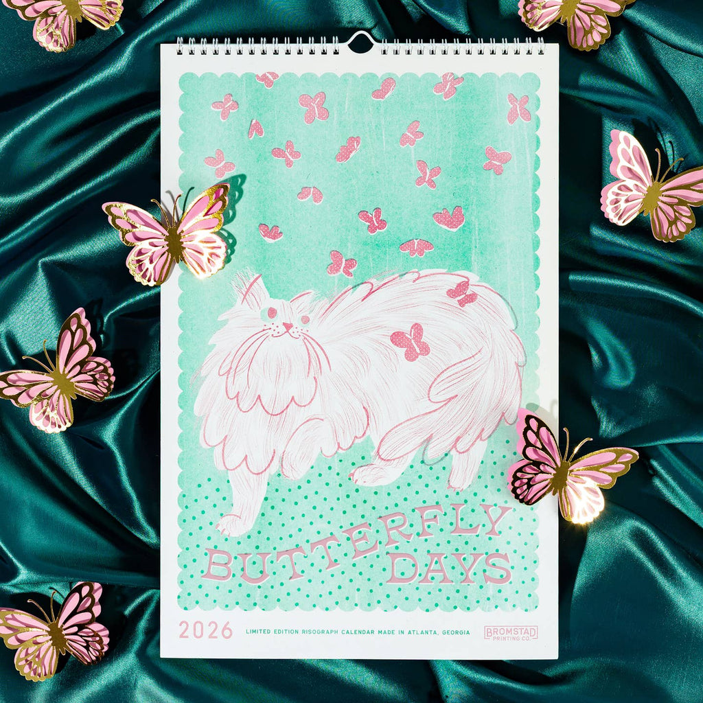 Calendar with green background and image of a white and pink fluffy cat with pink butterflies flying around it and pink text says, "Butterfly days".