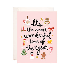 Pink background with images of gingerbread house, Santa, presents, snowman, and candles with black text says, “It’s the most wonderful time of the year”. White envelope is included.         