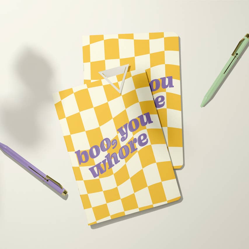 Image of notebook with yellow and white checkerboard background with purple text says, "Boo, you whore".