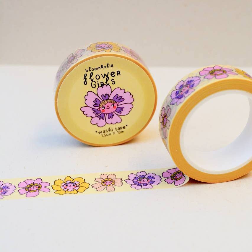 Image of roll of washi tape with yellow background and images of flowers in lilac, yellow. peach and pink with girls faces in the center. 