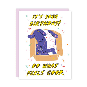 Greeting card with white background and purple cat inside cardboard box with yellow text says, "It's your birthday! Do what feels good.". Lilac envelope included. 