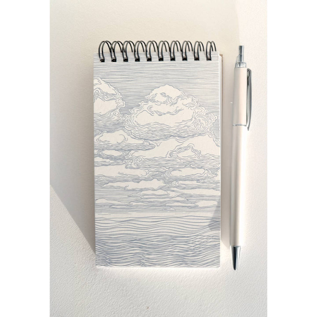 Notebook with black and white sketch of clouds on cover and coil binding at top. 