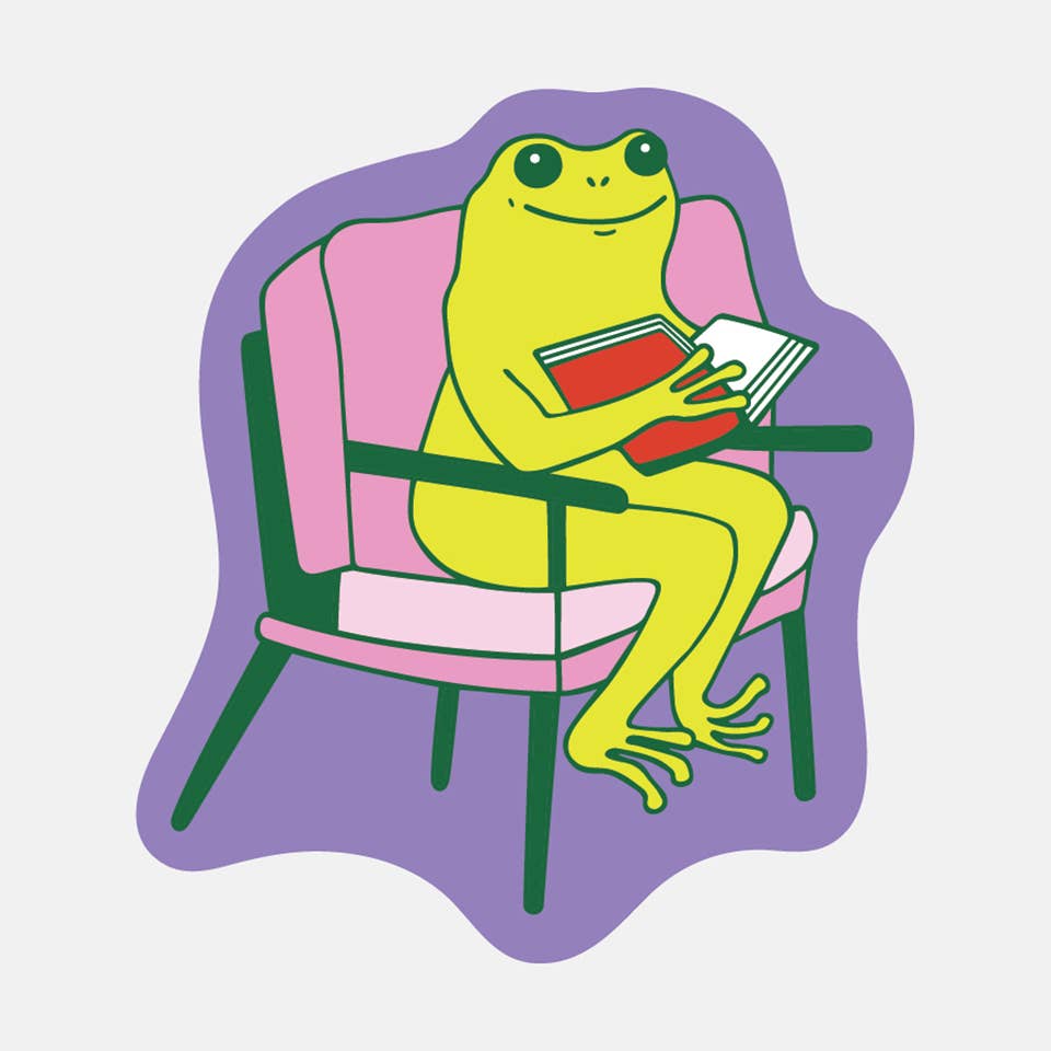 Decorative sticker with purple background and image of a green frog sitting on a pink and green chair reading a red book. 